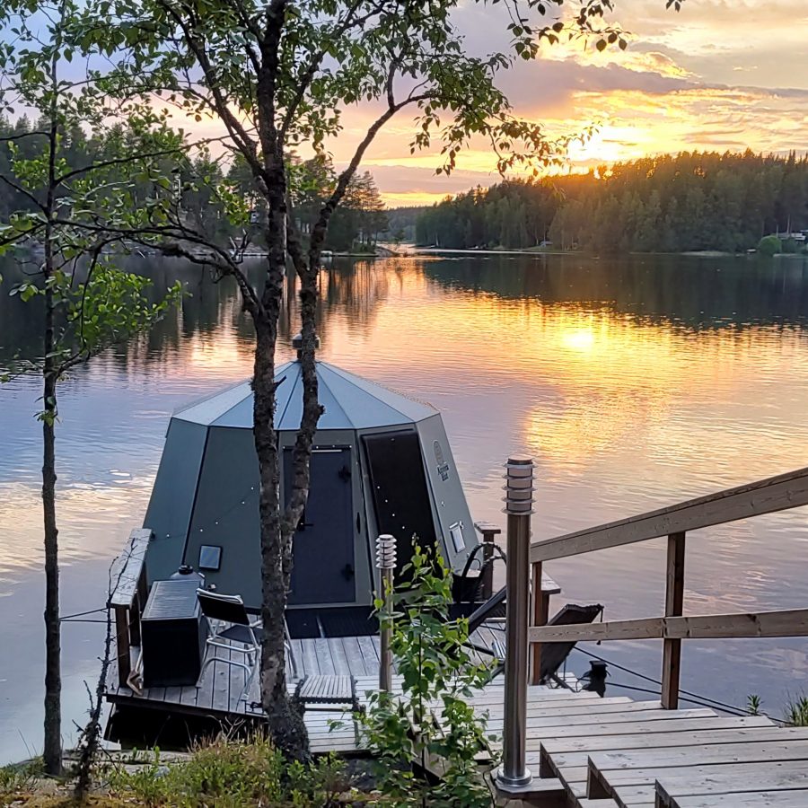 Yli-Kaitala Hut kelluu järvellä ja taustalla näkyy kaunis auringonlasku.